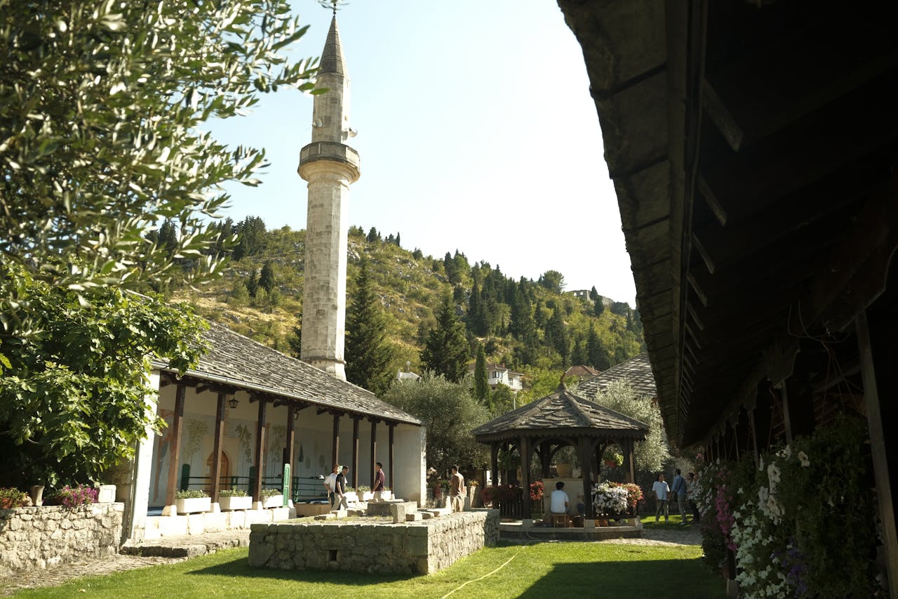 services-03 Beautiful mosque courtyard in Stolač, Bosnia surrounded by greenery under a clear blue sky.